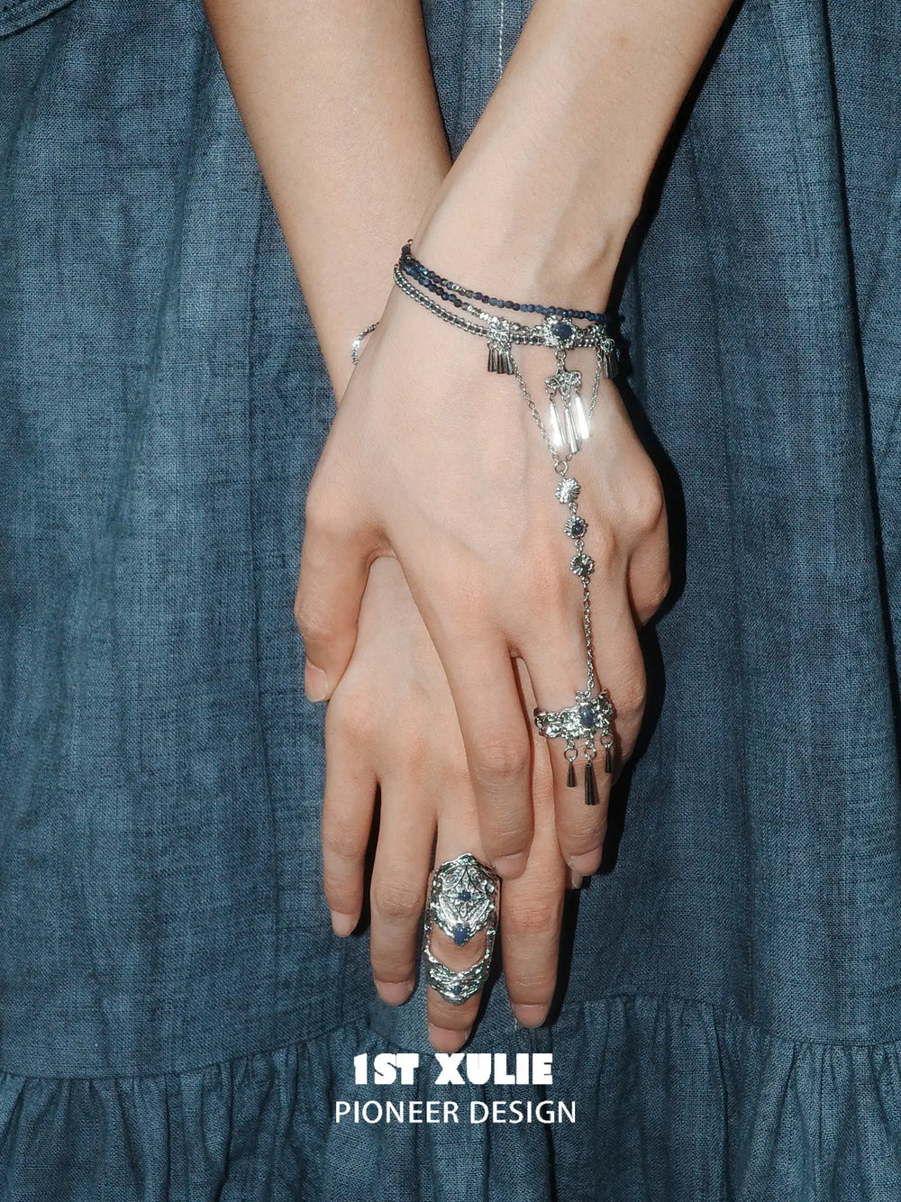 Blue stone bracelet-to-ring hand chain worn with coordinating jewelry