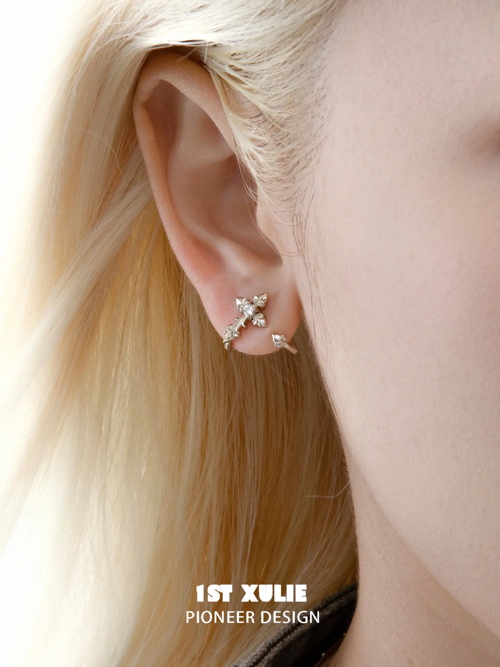 Detachable gold-toned fleur-de-lis earrings worn on the ear