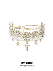 Layered gold-toned bracelet with white pearl beads and hanging fleur-de-lis charms