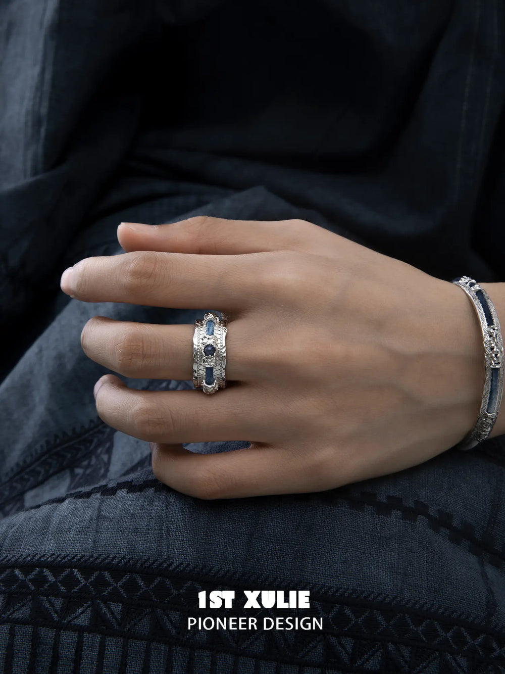 Wide blue woven open ring worn with coordinating jewelry