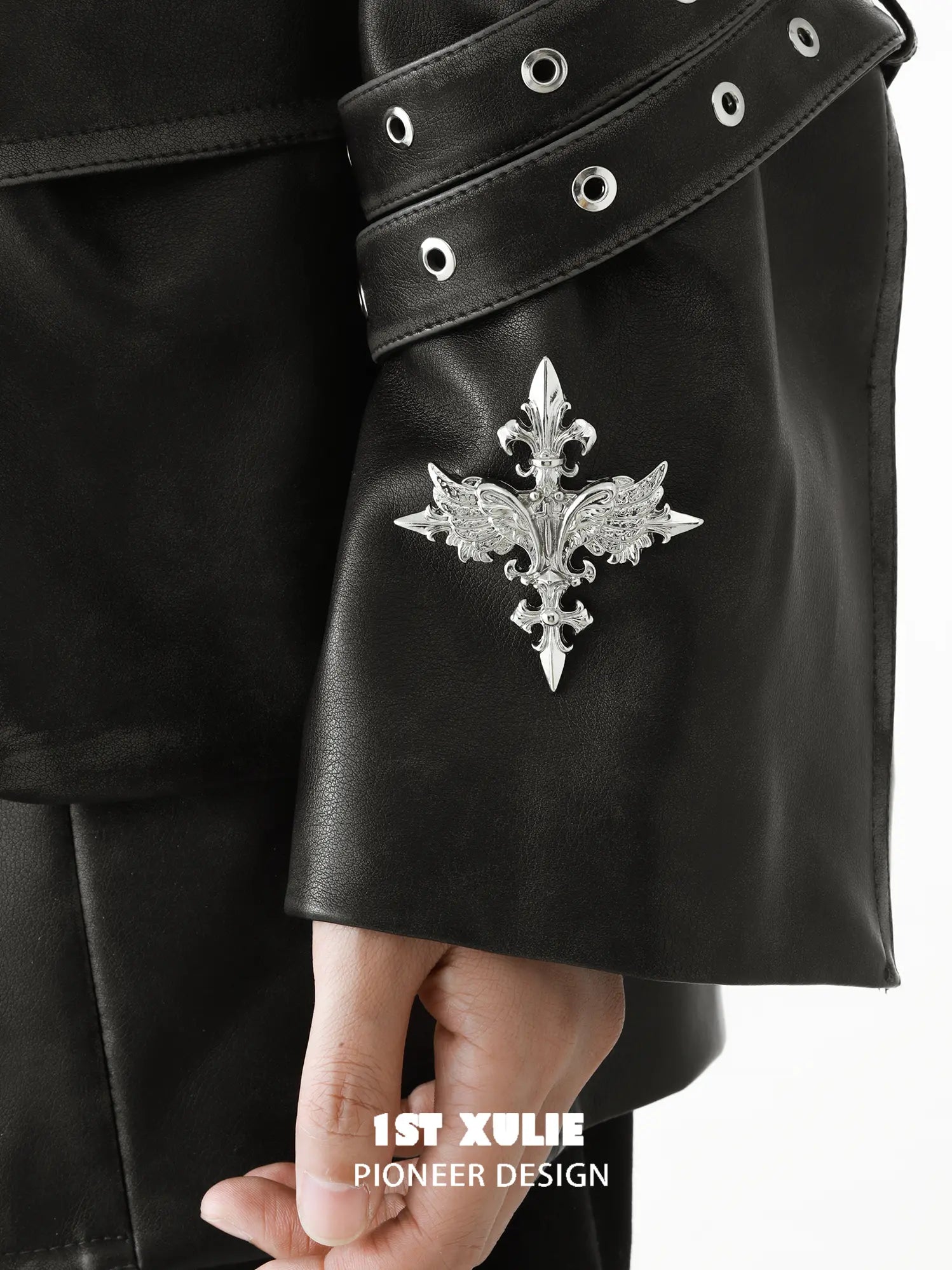 Silver-tone winged Fleur-de-Lis brooch styled on a black jacket sleeve.