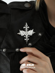 Close-up of the silver-tone Fleur-de-Lis brooch worn on a black jacket.