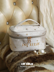 Light gray 1ST XULIE velvet makeup bag with gold star details and double zipper.