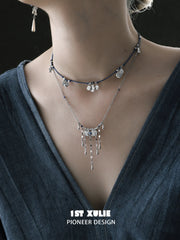 Close view of the blue cord necklace layered above the tassel necklace