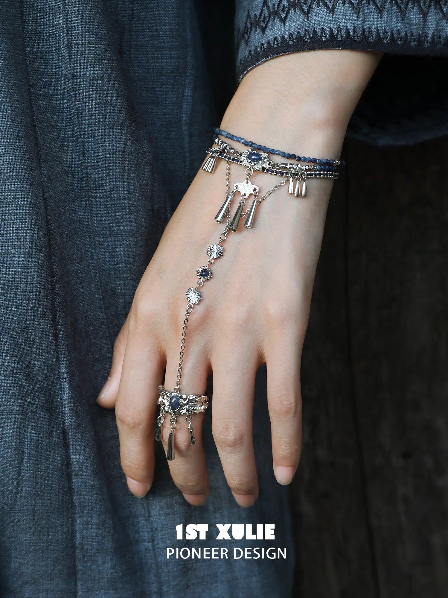 Blue stone bracelet-to-ring hand chain worn with coordinating jewelry