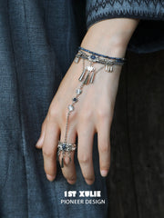 Blue stone bracelet-to-ring hand chain worn with coordinating jewelry