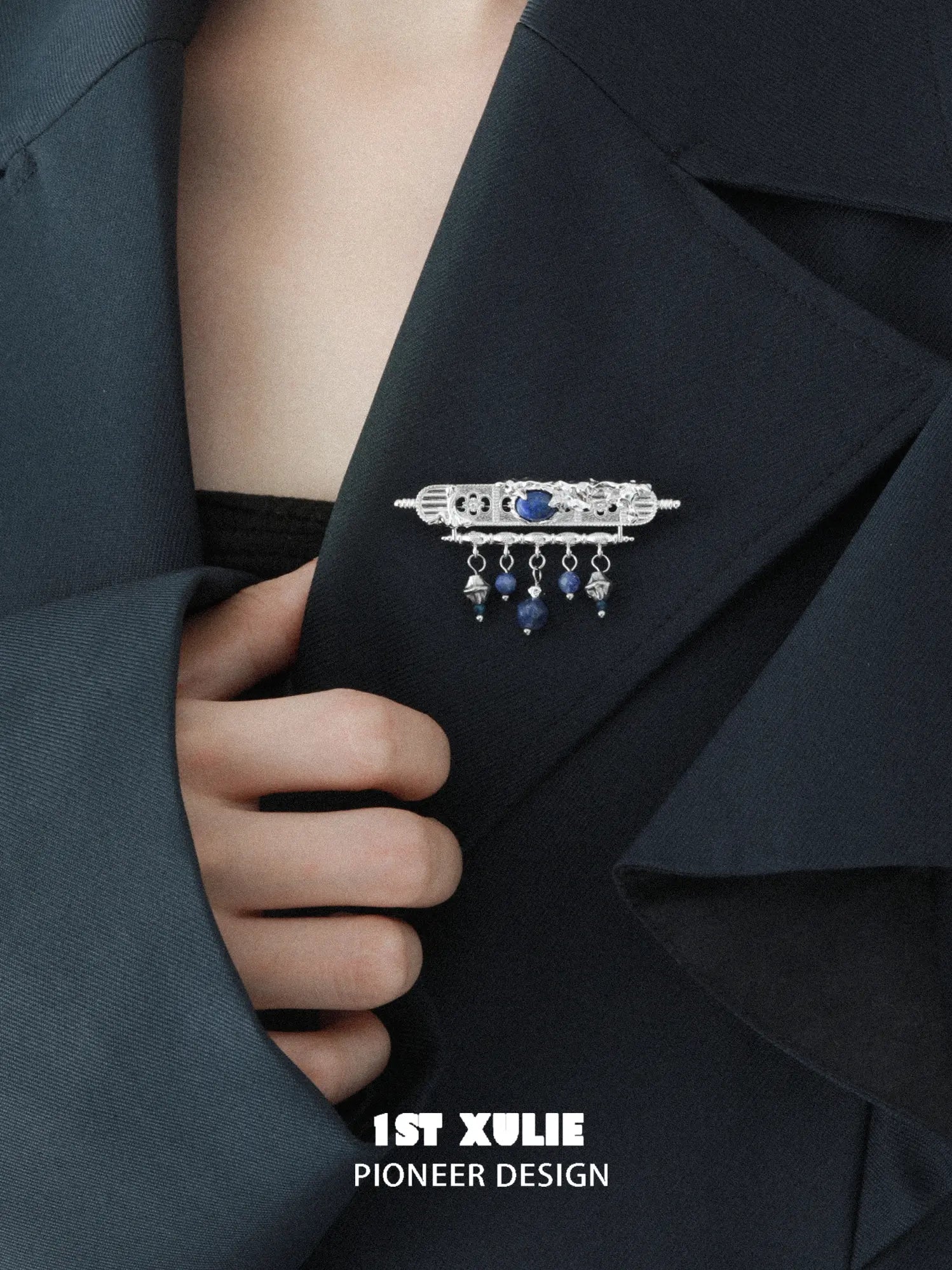 Blue stone tassel brooch pinned to a dark jacket lapel