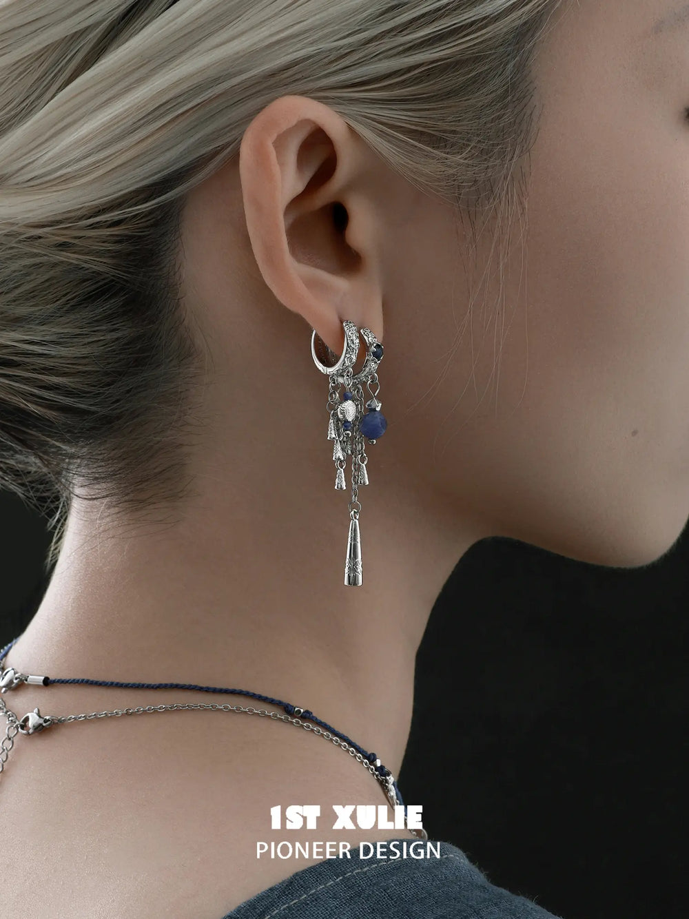 Close-up of the linked double-hoop and blue tassel earring worn on the ear