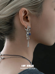 Close-up of the linked double-hoop and blue tassel earring worn on the ear