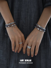 Narrow and wide blue woven rings worn with coordinating jewelry