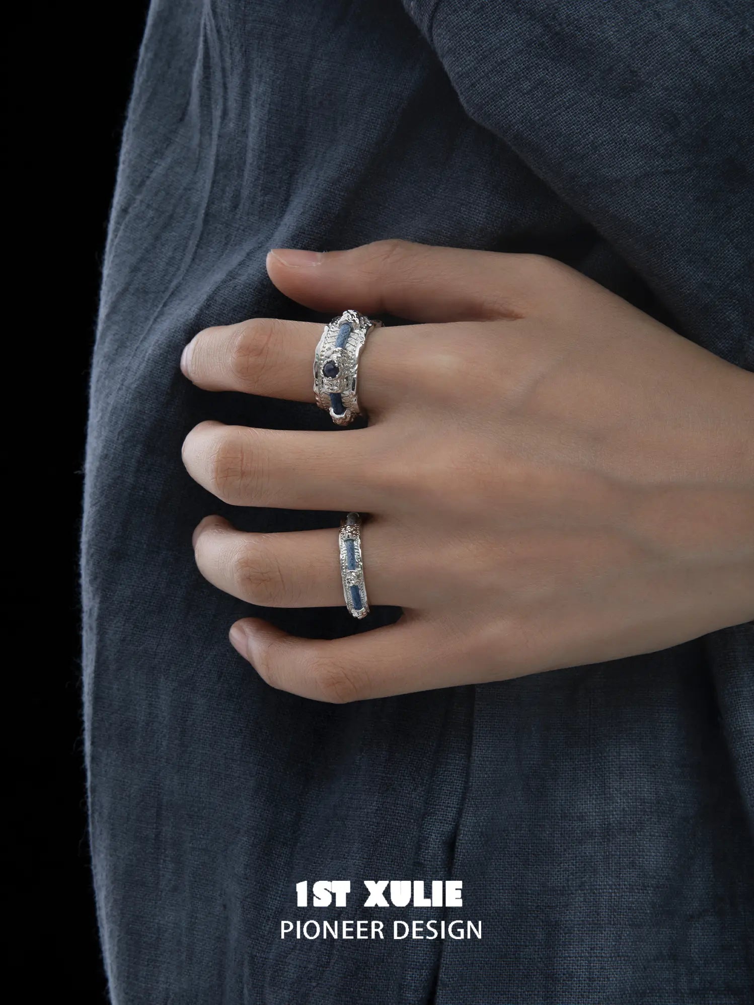 Narrow and wide blue woven rings worn together on the hand