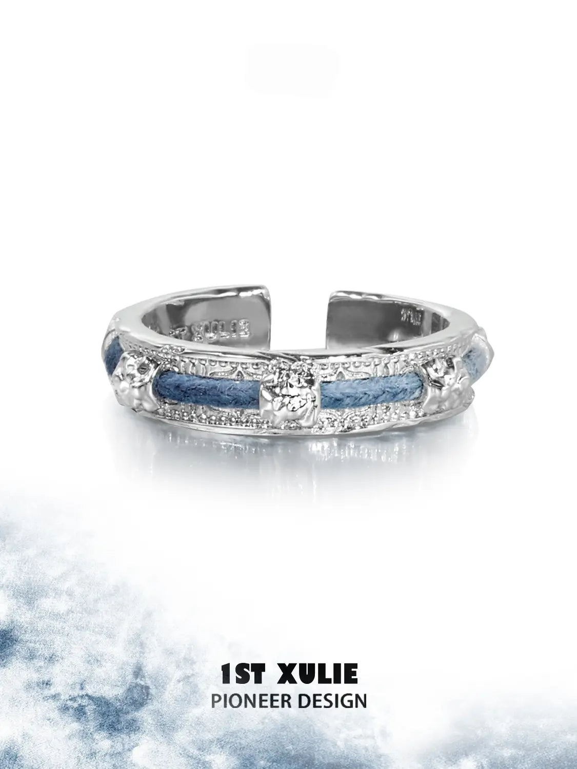 Narrow blue woven ring displayed against a light cloud-pattern background