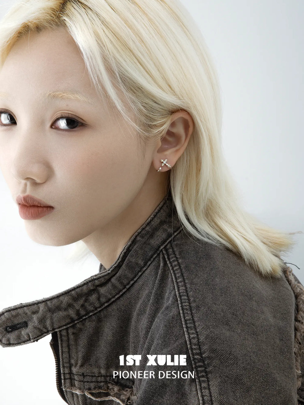Model wearing the compact gold-toned fleur-de-lis earring
