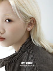 Detachable gold-toned fleur-de-lis earrings worn on the ear