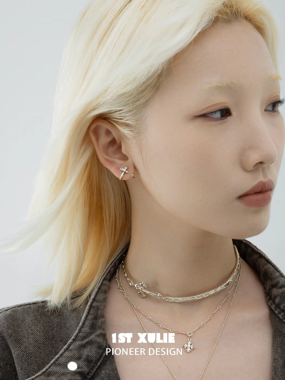 Detachable gold-toned fleur-de-lis earrings worn on the ear