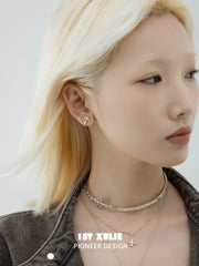 Detachable gold-toned fleur-de-lis earrings worn on the ear