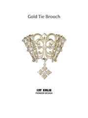 Gold-toned openwork tie brooch with a small clear-stone drop