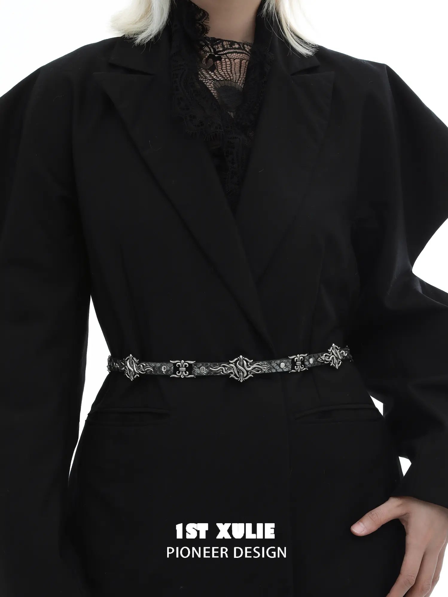 Fleur-de-lis chain belt worn over a dark blazer