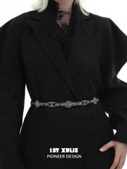 Fleur-de-lis chain belt worn over a dark blazer