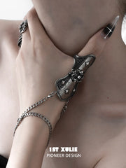 Gothic thumb armor ring and wrist chain worn with coordinating jewelry