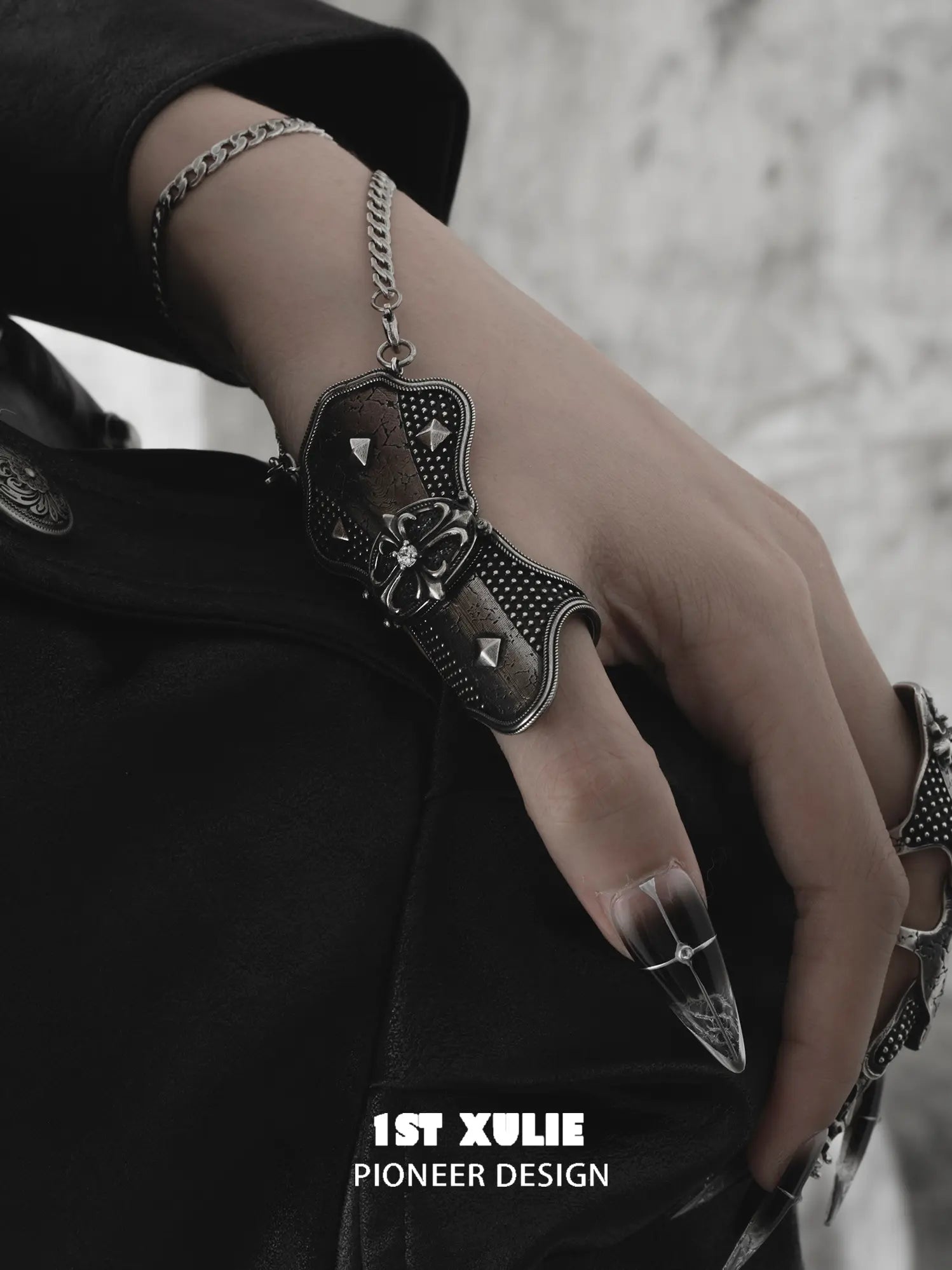 Gothic thumb armor ring and wrist chain worn with coordinating jewelry
