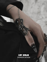 Gothic thumb armor ring and wrist chain worn with coordinating jewelry