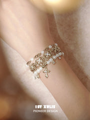 Layered pearl-bead and fleur-de-lis bracelet worn with coordinating jewelry