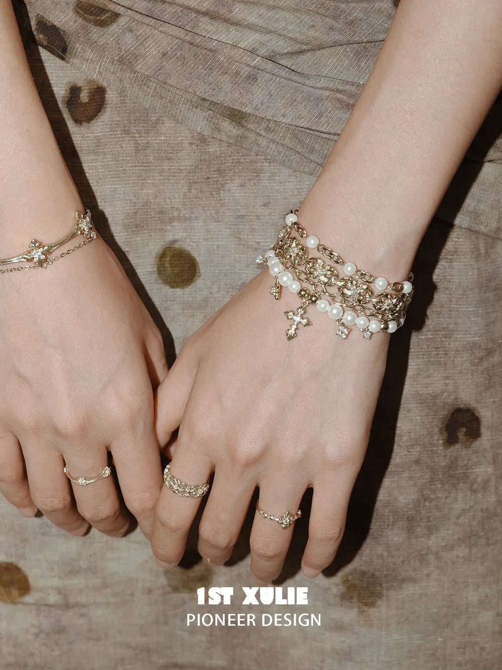 Layered pearl-bead and fleur-de-lis bracelet worn with coordinating jewelry