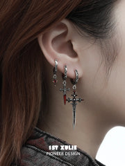 Red drop and dagger hoop earrings worn together on the ear